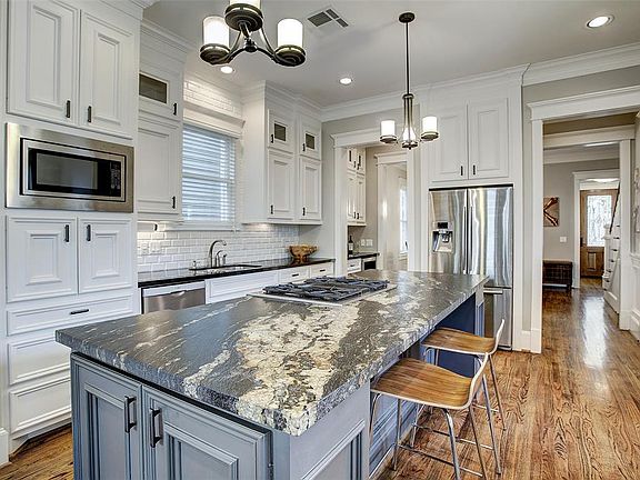 Kitchen has granite counters, stainless appliances, stylish tile backsplash, oversized breakfast bar with spectacular leathered 