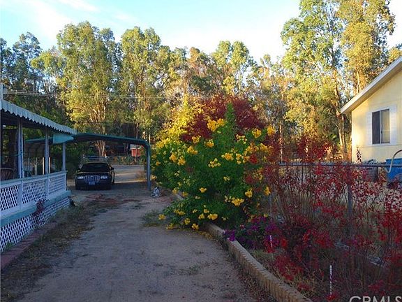 Beautiful Flowering Shrubs line the fence, pull thru to large double car garage/workshop towards center of property. Covered Carport, Eucalyptus Trees Surround.