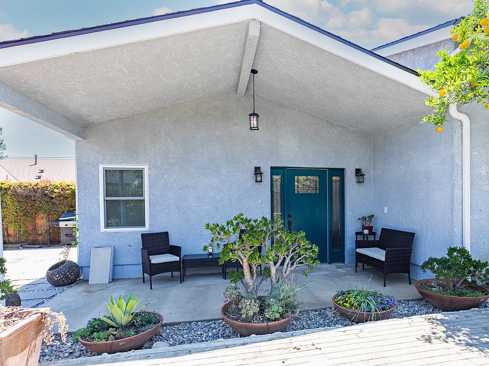 Front of the house with comfortable patio furniture to lounge and slip a cup of tea. Front french drain landscape design with succulents.