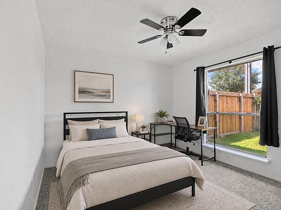 Well-sized bedroom with a large window, ceiling fan, and a dedicated desk area for work or study.