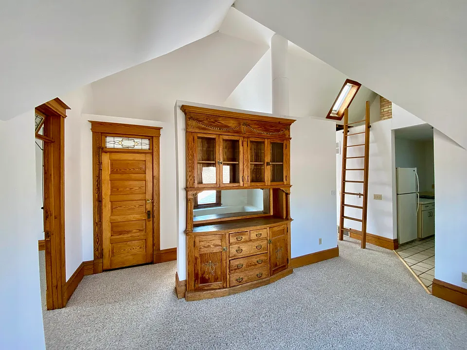 Dining room w/built-in hutch; entry door on left, ladder to loft and kitchen on right. Partially shown door on left goes to office/guest room. Double window behind the camera.