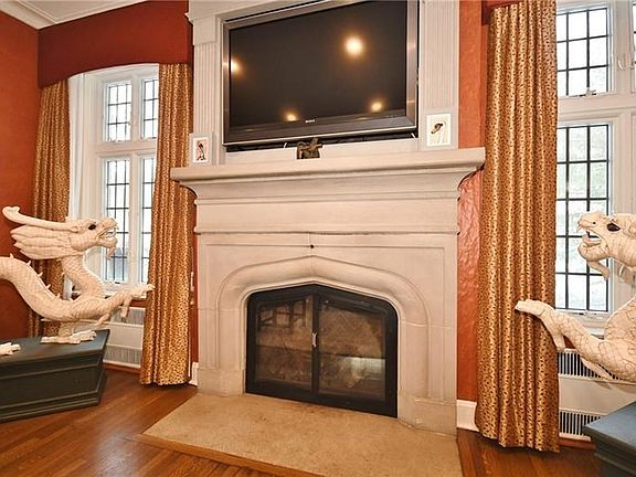 Stone fireplace is flanked by leaded glass floor to ceiling windows.
