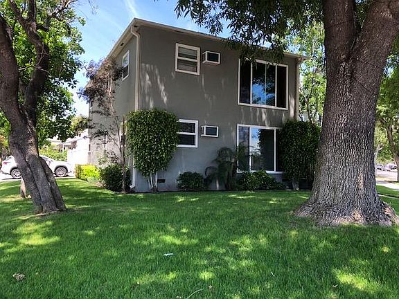 Building sits back off from sidewalk and is shaded and landscaped.