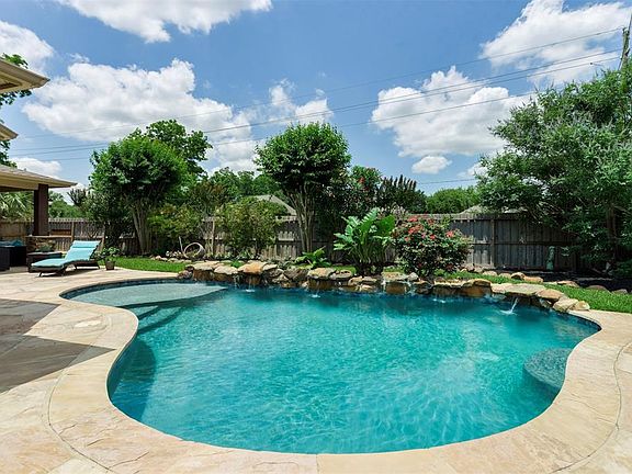 Exquisite poolside living! Weeping waterfall, flagstone patio, cathedral covered patio with complete summer kitchen! All backs to quiet open green space!