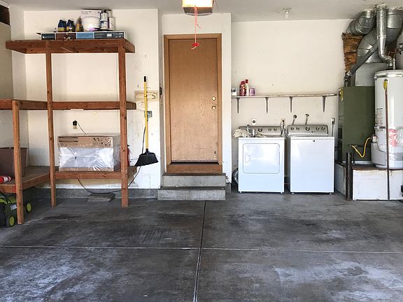 Washer and dryer in two car garage, together with some built in storage shelving.