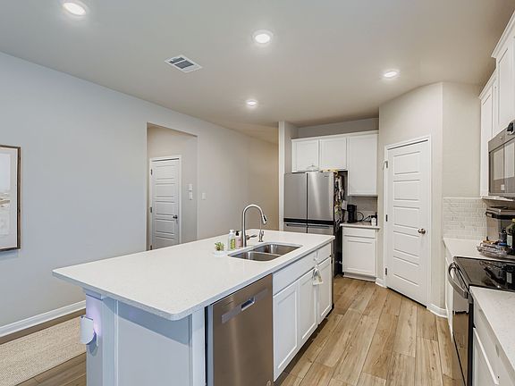 Kitchen appointed with stainless steal appliances, a walk-in pantry, and an abundance of cabinet storage.