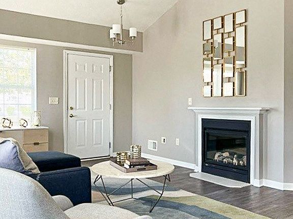 View of living area in ranch townhome great room with fireplace, cathedral ceiling, and faux hardwood floors