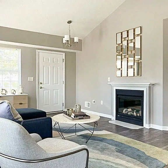 View of living area in ranch townhome great room with fireplace, cathedral ceiling, and faux hardwood floors