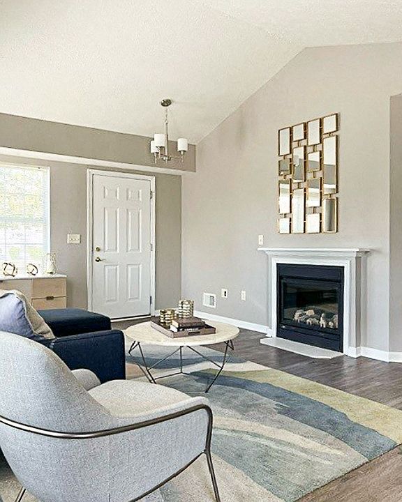 View of living area in ranch townhome great room with fireplace, cathedral ceiling, and faux hardwood floors