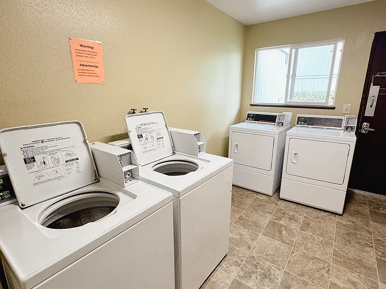 Shared laundry room with coin operated machines.