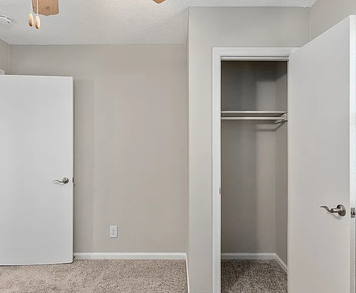 Step into elegance with this bright and airy bedroom, featuring a spacious closet and modern ceiling fan.