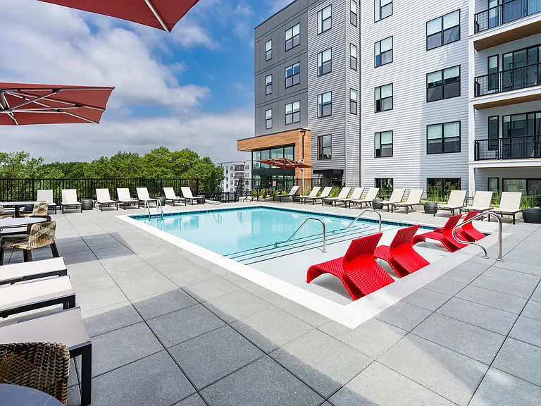 Resort-inspired poolside seating with bold red loungers at Modera LoSo.