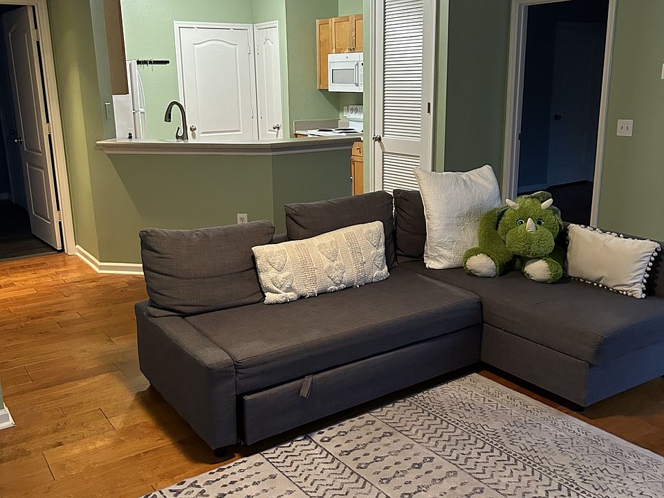 Living room with kitchen in the distance. Door leads to master bedroom.