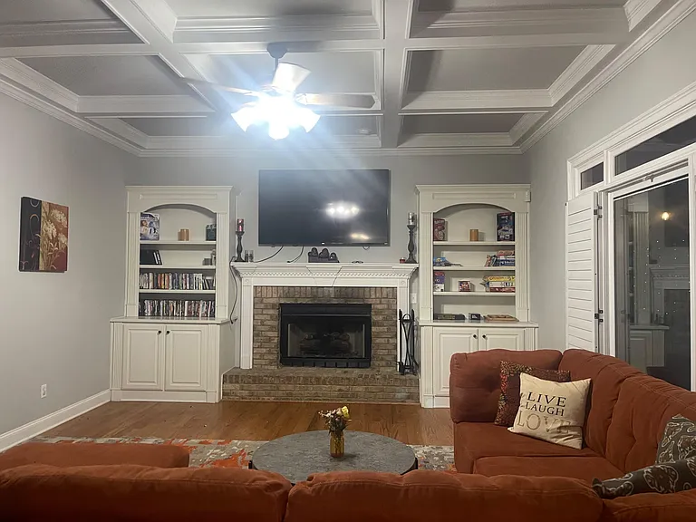 Spacious living room with a fireplace focal point, built-in shelving, and a mounted TV, plus access to a covered porch.