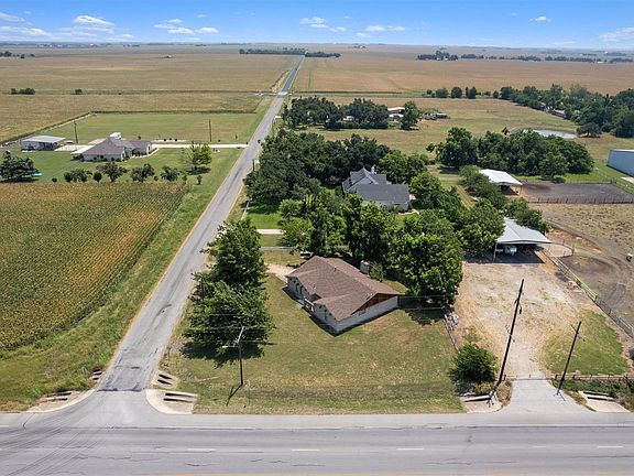 Expansive parcel featuring mature trees and a long driveway, surrounded by agricultural land