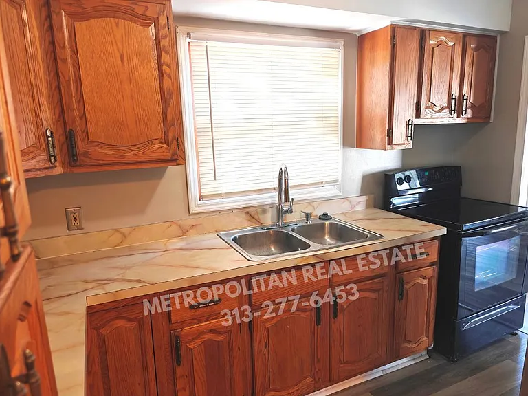 Kitchen sink and stove, fridge on opposite wall