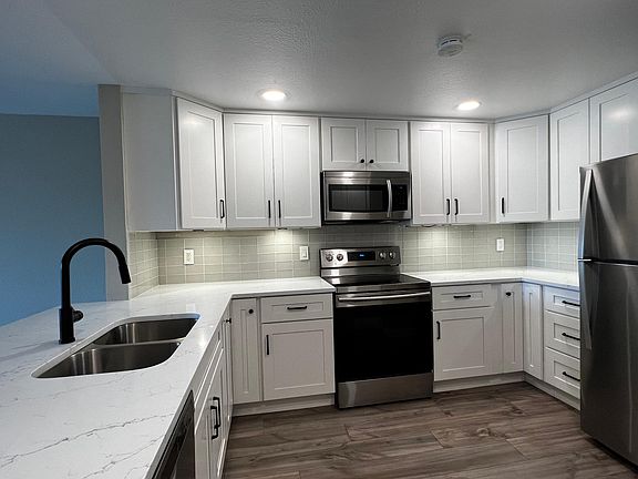 Open and spacious kitchen with lots of storage, quartz countertops, tile backsplash, ample lighting, stainless steel appliances, and matte black fixtures