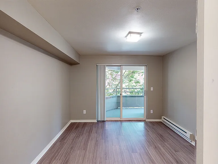Spacious apartment bedroom with wood-style flooring and patio access.