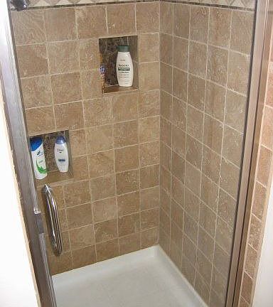Natural Stone tiled shower with new fixtures and door