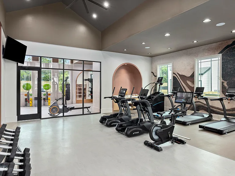 Modern apartment fitness center with cardio equipment, strength training, and dedicated stretch studio space.