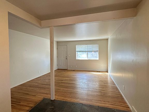 Front room with large window that provides natural light into living room/kitchen area. Hardwood in living room and stone tile in kitchen.