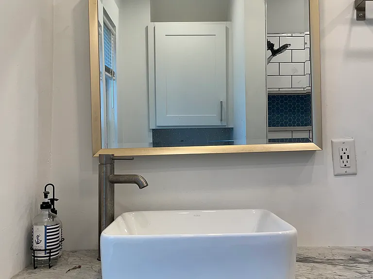 Updated full bathroom with a modern vanity, vessel sink, stylish mirror, and clean contemporary finishes.