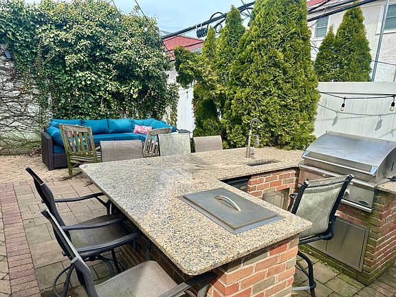 Backyard with bar, ice chest, direct gas grill, and couch
