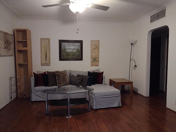 Living room fan, couch. paintings, and door to rest of the house
