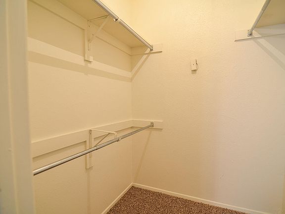 A large walk in closet with multiple shelves and hanger rods