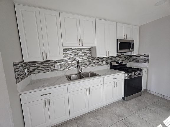 Brand new kitchen with stainless steel gas range, microwave oven, and refrigerator.