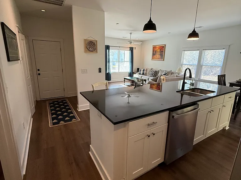 Open concept kitchen, living, and dining room with laundry on the left and door to attached garage straight ahead