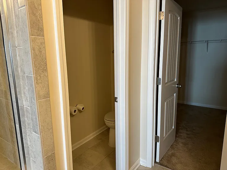 A closer view of the toilet room and the walk in closet entry from within the main bathroom.