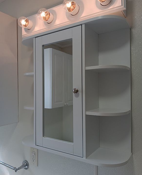 Bright bathroom with vanity, and several wall cabinets for extra storage.