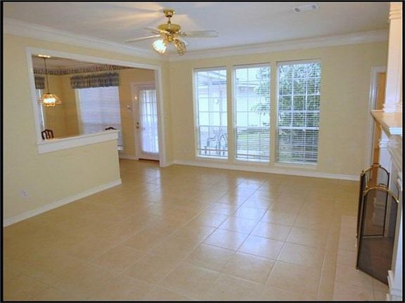 Spacious family room with wall of windows, open to kitchen & ceiling fan.