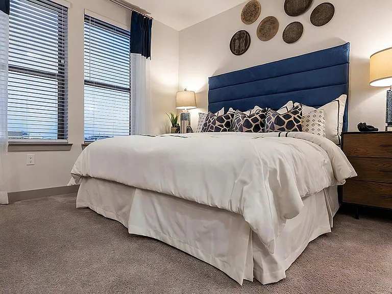 Spacious Carpeted Bedroom Featuring Large Windows and Soft Lighting