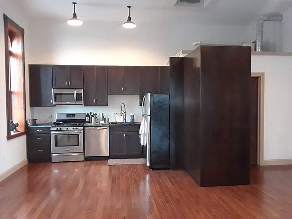 Galley kitchen with soapstone countertops. The stacked high efficiency washer and dryer are enclosed by the panel at the right.