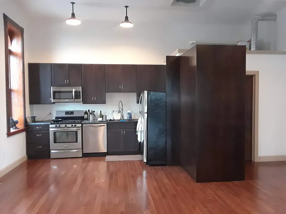 Galley kitchen with soapstone countertops. The stacked high efficiency washer and dryer are enclosed by the panel at the right.