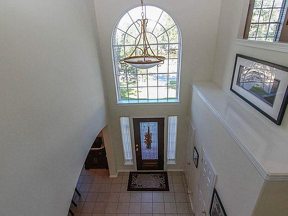 The entry features decorative ledges, a chandelier and arched window and tile floors.