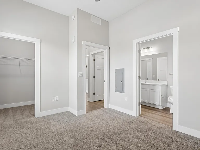 Carpeted bedroom, closet, and attached bathroom with ceiling fan of a Tiffany Flats apartment home.