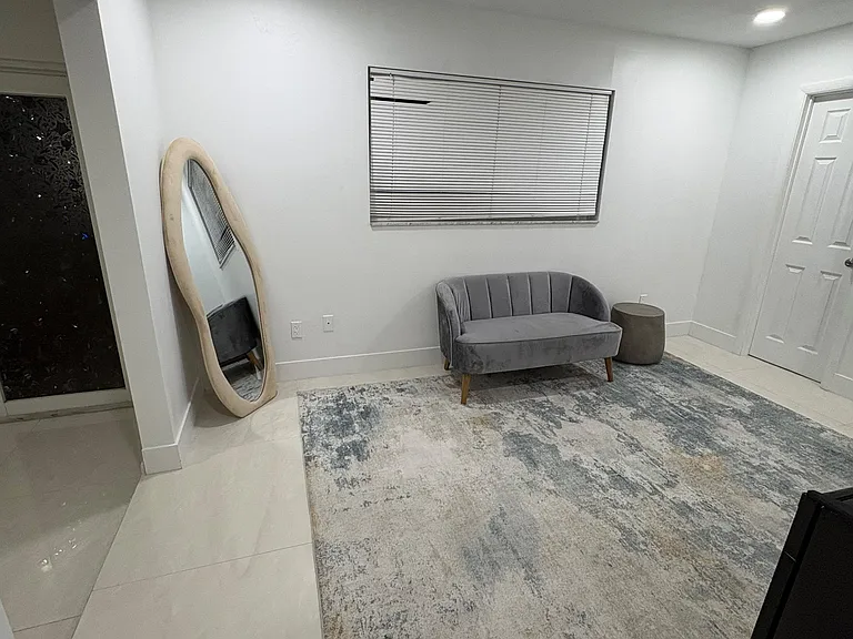 Compact sitting area with tile flooring, a window with blinds, and space for a loveseat or reading nook.