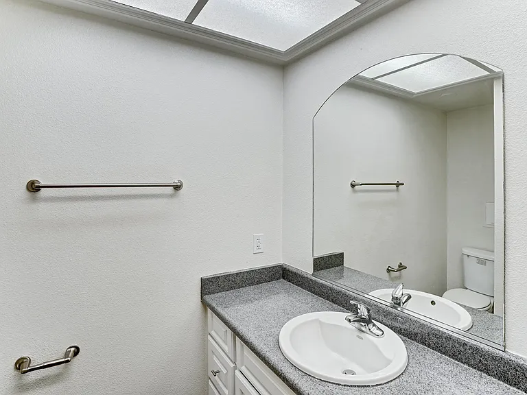 A bathroom with a sink, mirror, and towel rack.