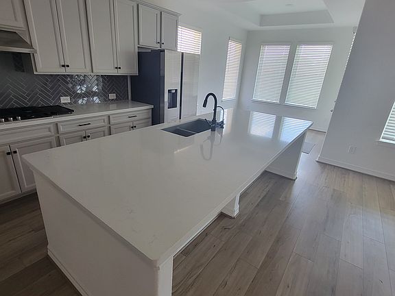 The heart of the home boasts a chef's kitchen with stainless steel appliances, quartz countertops, custom cabinetry, and a large island, perfect for meal preparation and entertaining
