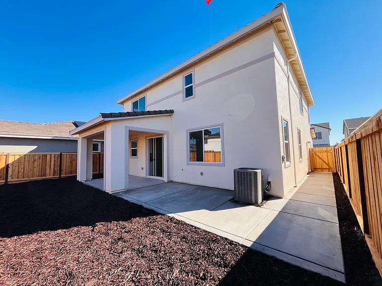 Backyard with extended concrete and low maintenance mulch