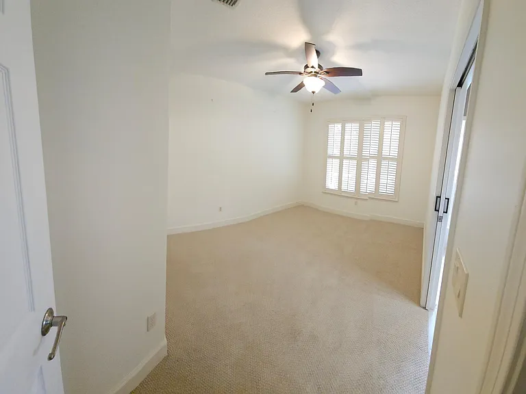 Bedroom 2 with full ensuite bathroom, ceiling fan, wood shuttered windows, and closet.