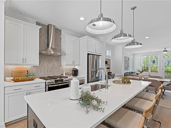 Kitchen featuring wall chimney exhaust hood, stainless steel appliances, open floor plan, recessed l