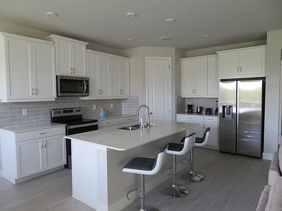 The fully equipped kitchen showcases high-end cabinets, quartz counter tops, stainless steel appliances, and walk-in pantry.