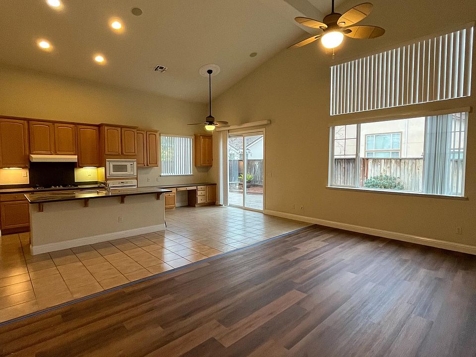 Additional open space great room, workspace area with desk, adjacent to kitchen and breakfast nook area, view of low maintenance backyard