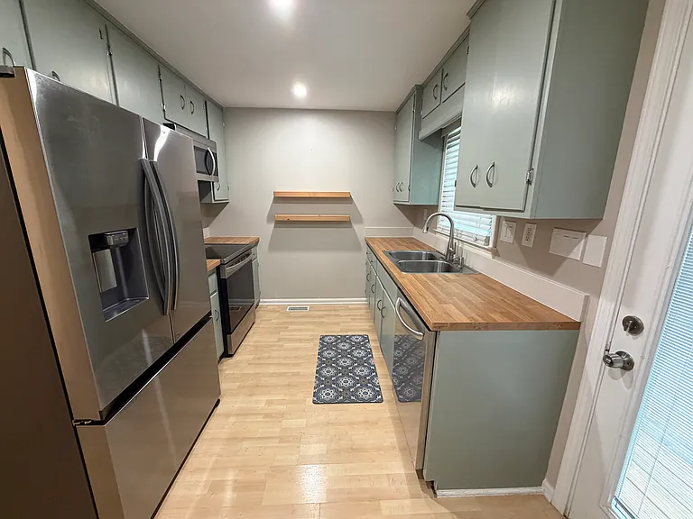 Kitchen with large fridge/freezer, oven, dishwasher, microwave, and plenty of natural light. Door goes out to the fenced in deck.