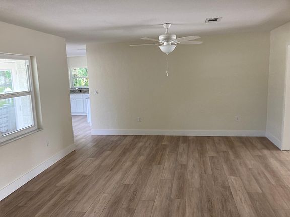 Large living room with new flooring, ceiling fans, and windows.