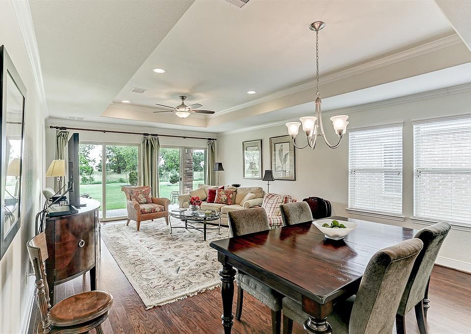 Dining room and living room with wood floors, tray ceiling, crown moulding, double glass sliders and ceiling fan